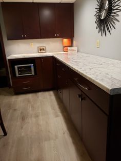 a kitchen with wooden cabinets and marble counter tops, along with a clock mounted on the wall