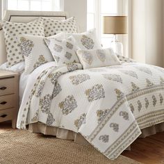 a bed in a bedroom with white and gold comforter set on top of it