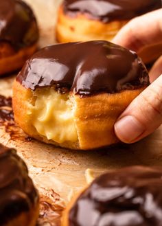 there is a hand that is picking up a donut with chocolate icing on it