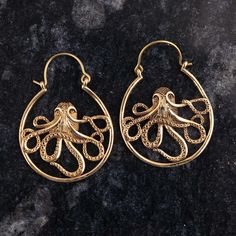 an image of gold earrings with an octopus on the front and back side, sitting on a black surface