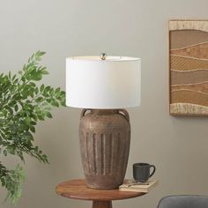 a table lamp sitting on top of a wooden table next to a potted plant