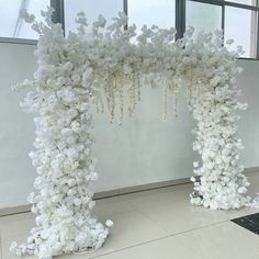 an arch made out of white flowers in front of a window