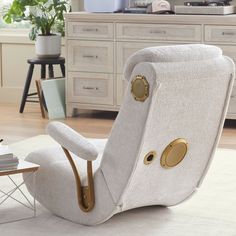 a white chair with gold buttons on the armrests in a living room setting