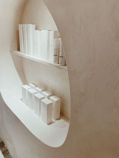 some books are sitting on shelves in a white walled room with marble floors and walls