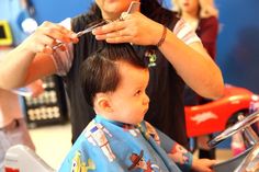 a little boy getting his hair cut by an adult