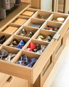 an open drawer in a closet filled with shoes and ties on top of wooden drawers