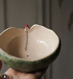 a hand holding a ceramic bowl with a tiny bird on it's side and the word i love you written in cursive