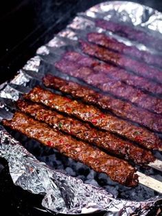 several skewered meats are being cooked on an outdoor grill