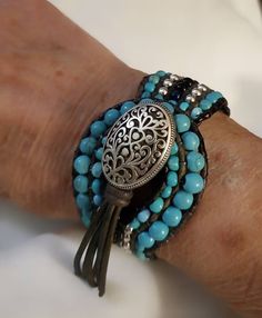 I design and create all the jewelry in my collection and find inspiration in the work of Native American artisans.  This beautiful handcrafted cuff bracelet may be custom created to accommodate any size wrist. It boasts rows of turquoise colored Howlite, black jasper and silvertone beads entwined with six  strands of deep slate leather cord. The ornate silvertone toggle closure is encircled by graduated Howlite beads. This bracelet measures 1-1/8" in width and 7-1/2" in length. P.S. I love this Southwestern Adjustable Cuff Bracelet With Natural Stones, Bohemian Turquoise Cuff Bracelet With Round Beads, Handmade Turquoise Wrap Bracelet, Artisan Turquoise Hand Wrapped Wrap Bracelet, Adjustable Southwestern Turquoise Cuff Bracelet, Adjustable Turquoise Southwestern Cuff Bracelet, Artisan Hand Wrapped Turquoise Wrap Bracelet, Artisan Beaded Turquoise Cuff Bracelet, Artisan Turquoise Beaded Cuff Bracelet