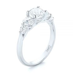 a three stone engagement ring with diamonds on the shoulders and side stones in white gold