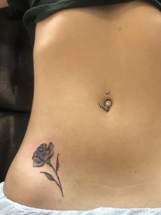 a woman's stomach with a rose tattoo on the side and a diamond in the middle