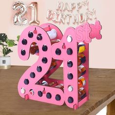 a wooden table topped with a pink and black number twenty two bottle holder filled with bottles