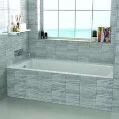 a bath tub sitting next to a window in a bathroom with tile walls and floor