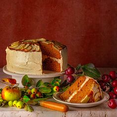 a cake sitting on top of a table next to other cakes and fruit, with one slice cut from the cake