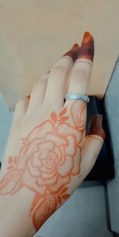 a woman's hand with an orange and white flower tattoo on her left arm