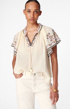 Loose and subtly transparent, the Valentin blouse is perfect for summer. Its Tunisian collar and embroidery are sure to bring a folk style to your outfits. This ruffled piece has a slightly A-line shape and butterfly sleeves for an ultra-summery look.Blouse with short, ruffled sleeves.Ruffled collar with drawstring ties.Unlined.Muna is 1.77m tall and wears a size 36.Composition : Main material: 100% cotton. Main lining: 100% cotton. Embroidery: 100% polyester. Folk Style, Western Tops, Folk Fashion, Vanessa Bruno, Ruffled Collar, Butterfly Sleeves, Ruffled Sleeves, Cardigan Coat, Active Wear Tops