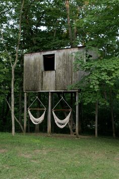 two hammocks in front of a wooden structure with a window on the side