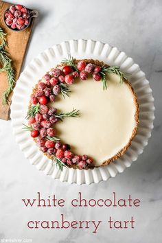 a white plate topped with a cheesecake covered in cranberries and greenery