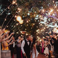 a newly married couple kiss as they walk down the aisle with sparklers