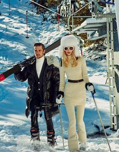 a man and woman walking in the snow with skis