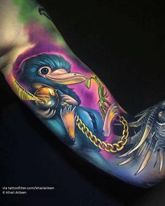 a person with a colorful tattoo on their arm holding a bird and chain around his neck