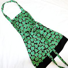 a green and black apron on a white bed