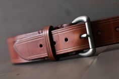 "These every day leather belts are made using thick, durable, full-grain harness leather from the Wickett & Craig tannery. Designed to be at your service for many years, they will take on a wonderful rich character with age. They're 1.5\" in width, with a tapered, low profile tail-end. Its hand-stitched construction is fitted with a solid brass buckle with a muted, satin-steel finish. For added comfort and durability, all edges are rounded and burnished smooth with a soft wax finish. Handcra Masculine Leather Strap Belts For Business, Masculine Leather Business Belts, Rugged Distressed Brown Leather Belt, Luxury Rugged Leather Belt, Rustic Brown Hand-tooled Belt, Custom Leather Belts, Handmade Guitar, Leather Craftsmen, Wide Leather Belt