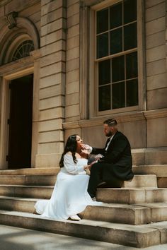 a bride and groom sitting on the steps of an old building