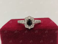 an oval cut black and white diamond ring on top of a red velvet display case