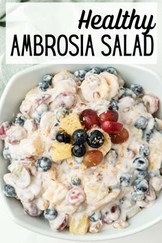 a white bowl filled with fruit salad and the words healthy ambrosia salad above it