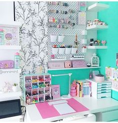 a room filled with lots of crafting supplies on shelves next to a white desk