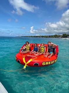 a group of people riding on top of an inflatable raft through the ocean