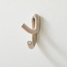 a white wall with a small ceramic object on it's side and the letter j in the middle