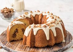 a bundt cake with white icing and walnuts on a wooden platter