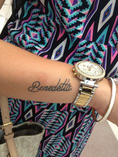 a woman with a wrist tattoo that says benedella on her left arm and the word benedella written in cursive font