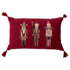 three nutcrackers embroidered on a red pillow with tasselled fringes