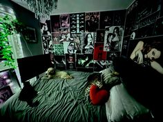 a dog laying on top of a bed next to a wall with pictures and posters