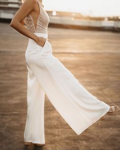 a woman standing on top of a parking lot wearing a white dress and high heels