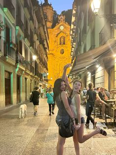 two young women are dancing in the street