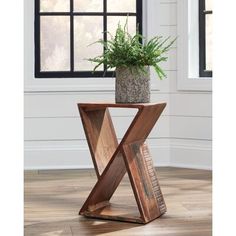 a plant in a pot sitting on top of a wooden table next to a window