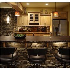 a kitchen with stone counter tops and bar stools in front of an island that has lights hanging from the ceiling