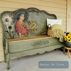 a painted bench with flowers and a basket on the ground in front of a house