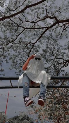 a person hanging upside down in the air with their feet up on a rail and trees behind them