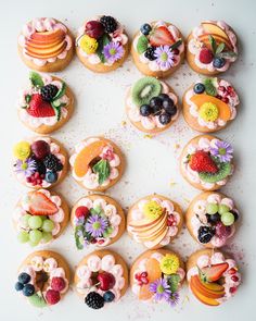 there are many decorated donuts on the white table with flowers and fruit in them