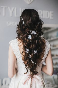 the back of a woman's head wearing a wedding dress with flowers in her hair