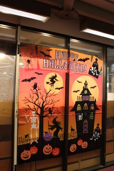 a window decorated for halloween with pumpkins, bats and witch's on it