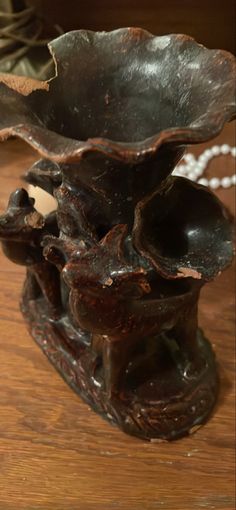 a metal vase sitting on top of a wooden table