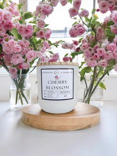 some pink flowers are in vases next to a white candle on a wooden stand