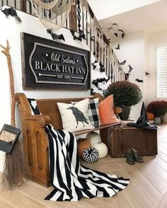 the entryway is decorated for halloween with black and white decor, pumpkins, striped throw pillows, and witch hats