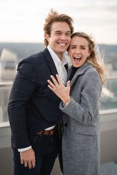 a man and woman standing next to each other with their arms around each other smiling